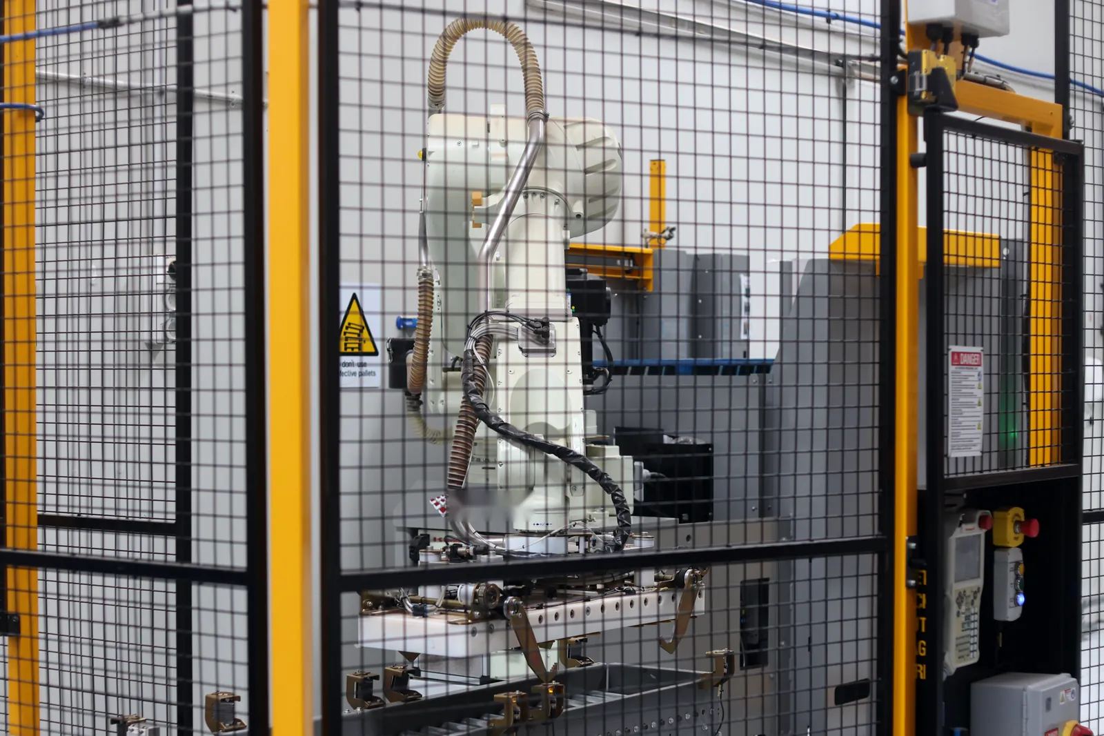 A robot arm inside its safety cage on the packing line